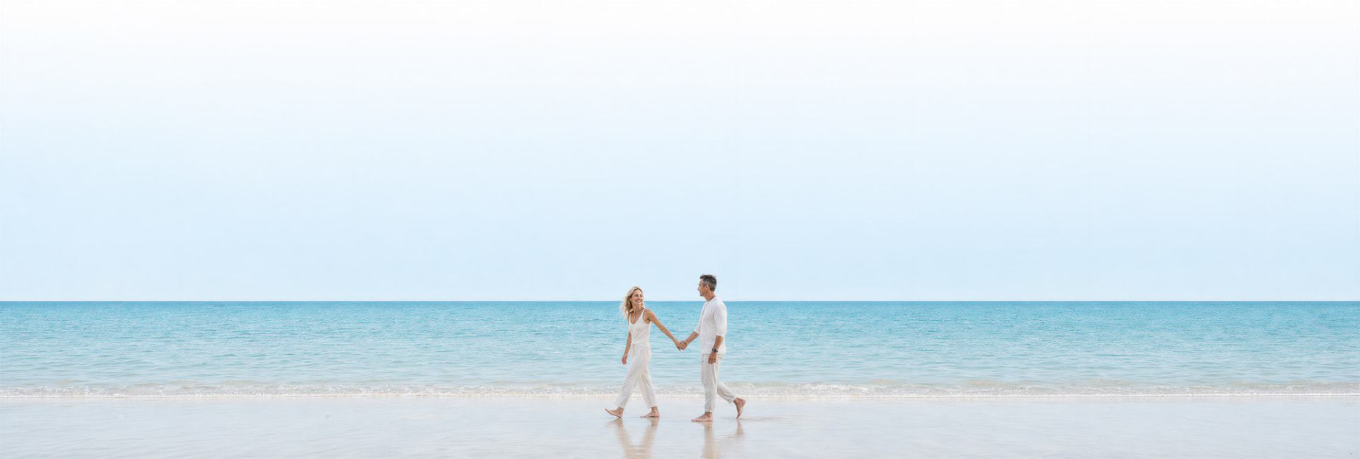 Couple walking on a wide, calm beach